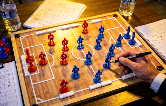 足球战术板上摆放球员棋子进行赛前战术分析的画面
